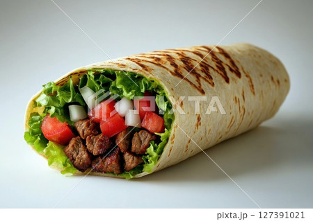 Close-up of a freshly made beef burrito filled with colorful ingredients like cheese, tomatoes, and cilantro against a plain white background. 127391021