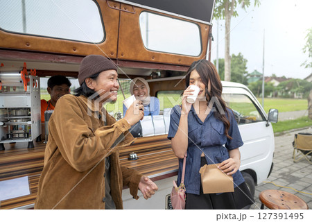 Indonesian southeast asian couple enjoying coffee in front of the coffee shop. A small business of a coffee shop or cafe on a truck 127391495