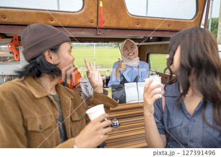 Indonesian southeast asian couple enjoying coffee in front of the coffee shop. A small business of a coffee shop or cafe on a truck 127391496