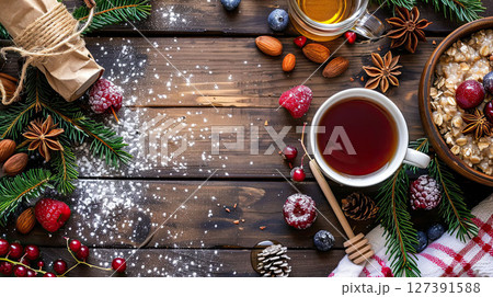 Flat lay of healthy breakfast with oatmeal, berries, honey, tea and fir twigs served on wooden table 127391588