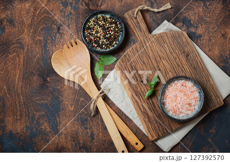 Wooden kitchen utensils and spices. Wooden spoons, cutting board, napkin and spices on a old wooden table. Top view, copy space. Wooden kitchen utensils and spices. Wooden spoons, cutting board, napkin and spices on a old wooden table. Top view, copy space. 127392570