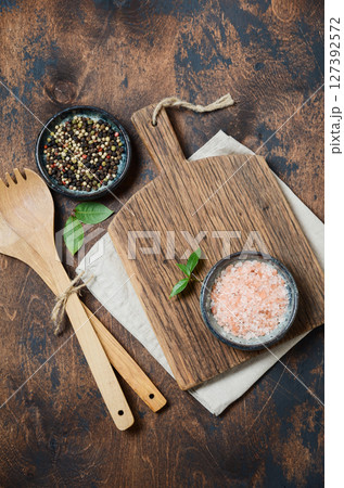 Wooden kitchen utensils and spices. Wooden spoons, cutting board, napkin and spices on a old wooden table. Top view.	 127392572
