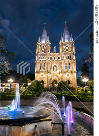 In Jardin, Colombia, the twin-spired Basilica of the Immaculate Conception glows gold at dusk as color-lit fountains arc in the leafy plaza before it. In Jardin, Colombia, the twin-spired Basilica of the Immaculate Conception glows gold at dusk as color-lit fountains arc in the leafy plaza before it. 127392895