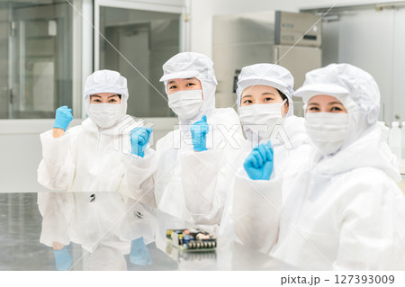 クリーンルームで精密機器を扱う防塵服姿の作業員男女 127393009