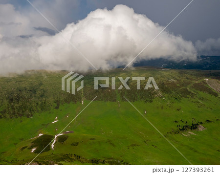 Big white clouds over a green mountain valley 127393261