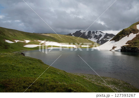 Small alpine lake and green meadows 127393267