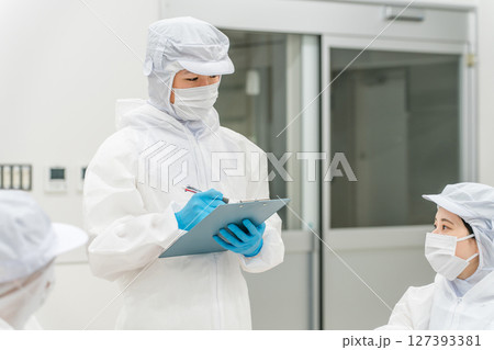 防護服,クリーンウェアを着る製造工場で働くスタッフの男女 防護服,クリーンウェアを着る製造工場で働くスタッフの男女 127393381