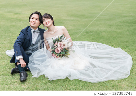 式場のガーデンの芝生に座るウェディングドレス姿の新婦と新郎(ウェディングフォト) 式場のガーデンの芝生に座るウェディングドレス姿の新婦と新郎(ウェディングフォト) 127393745