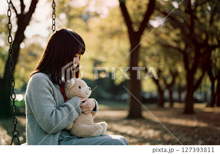 誰にも相談できずに孤立して家出をした少女。行き場がなく、公園のブランコに座っている 127393811