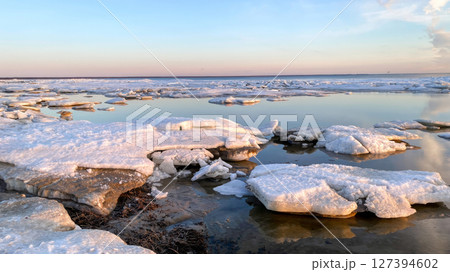 Beautiful winter landscape of a frozen sea coast at sunset 127394602