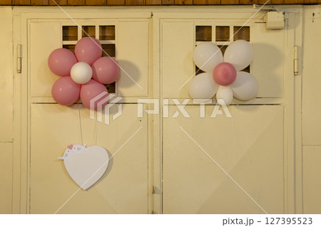 Pink and white flower shaped balloons hanging on a wall with heart shaped label Pink and white flower shaped balloons hanging on a wall with heart shaped label 127395523