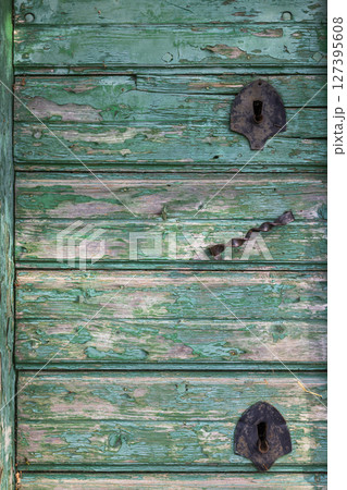 Old green wooden door with peeling paint and rusty metal hinges in Wildendurnbach, Lower Austria Old green wooden door with peeling paint and rusty metal hinges in Wildendurnbach, Lower Austria 127395608