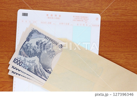 茶封筒に入れた千円札と預金通帳 127396346