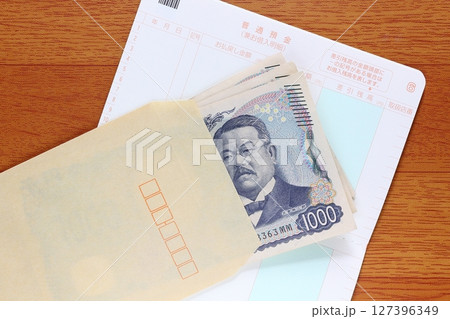 茶封筒に入れた千円札と預金通帳 127396349