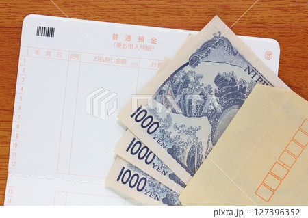 茶封筒に入れた千円札と預金通帳 127396352