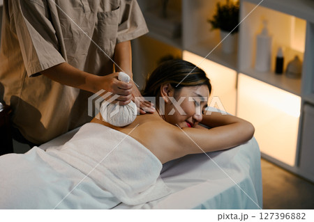 Therapist using a traditional herbal ball to relieve shoulder tension. Wellness concept Therapist using a traditional herbal ball to relieve shoulder tension. Wellness concept 127396882