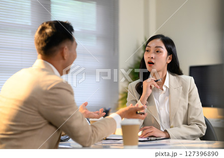 Business colleagues working together at laptop, discussing ideas and reviewing project data in an office 127396890