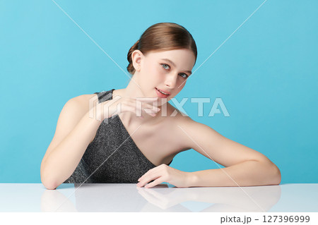 A beautiful young woman with clean, fresh skin against a blue background. Skincare, facial treatment, cosmetology, beauty, and spa. An elegant portrait of an woman. A beautiful young woman with clean, fresh skin against a blue background. Skincare, facial treatment, cosmetology, beauty, and spa. An elegant portrait of an woman. 127396999