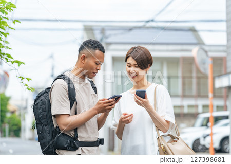 スマホの翻訳アプリを使って黒人男性と会話する日本人女性 127398681