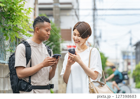 スマホの翻訳アプリを使って黒人男性と会話する日本人女性 127398683