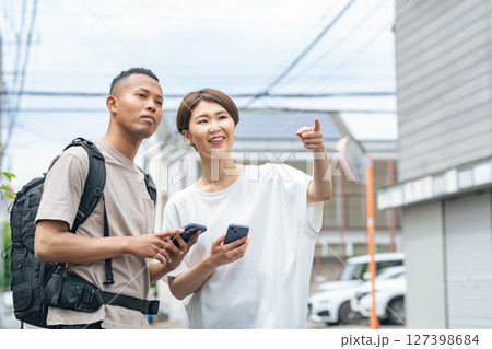 スマホを持って黒人男性に道案内する日本人女性 127398684