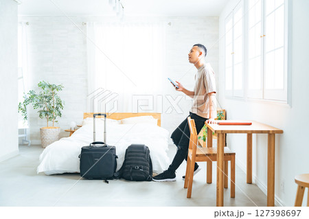 ホテルの部屋でスマホを見る黒人男性旅行者 ホテルの部屋でスマホを見る黒人男性旅行者 127398697