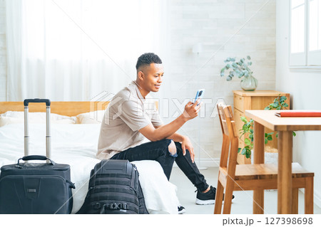 ホテルの部屋でスマホを見る黒人男性旅行者 127398698