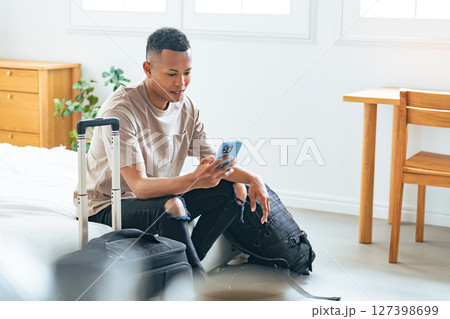 ホテルの部屋でスマホを見る黒人男性旅行者 127398699
