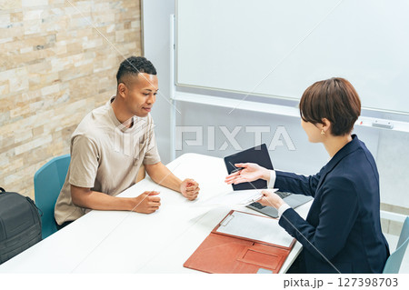 面談する黒人男性と日本人女性スタッフ 面談する黒人男性と日本人女性スタッフ 127398703