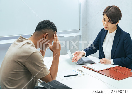 悩む黒人男性と面談する日本人女性スタッフ 悩む黒人男性と面談する日本人女性スタッフ 127398715