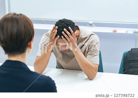 悩む黒人男性と面談する日本人女性スタッフ 悩む黒人男性と面談する日本人女性スタッフ 127398722
