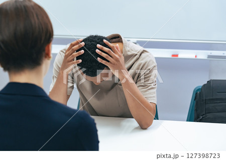悩む黒人男性と面談する日本人女性スタッフ 127398723