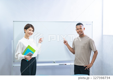 教室のホワイトボードを指さす黒人男性と日本人女性 127398734
