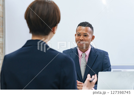 黒人男性ビジネスマンと面談する日本人女性スタッフ 黒人男性ビジネスマンと面談する日本人女性スタッフ 127398745