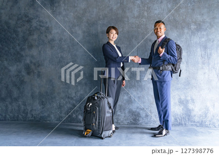 旅行の荷物を持って握手する黒人男性ビジネスマンと日本人女性スタッフ 127398776