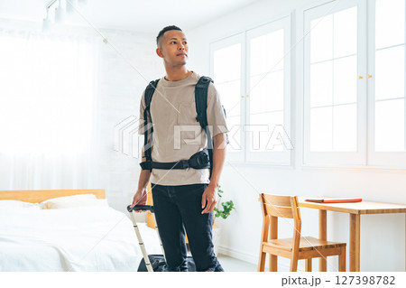 ホテルの部屋にスーツケースを持って立つ黒人男性旅行者 127398782