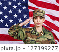 American female soldier in uniform saluting on a background USA flag. 127399277