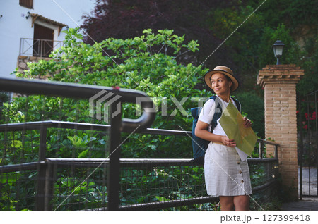 Young Woman Tourist Exploring a Charming Old Town with Map and Backpack Young Woman Tourist Exploring a Charming Old Town with Map and Backpack 127399418