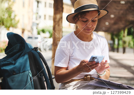 Woman Using Smartphone in Outdoor Setting Wearing Hat and Casual Clothes Woman Using Smartphone in Outdoor Setting Wearing Hat and Casual Clothes 127399429