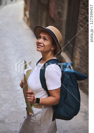 Woman Traveler Exploring a Historic Medieval City Street with a Map and Backpack 127399457