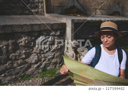 Tourist Exploring a Historic Stone Landmark While Studying a Map Outdoors Tourist Exploring a Historic Stone Landmark While Studying a Map Outdoors 127399482