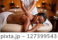 African woman having a back massage at a cosmetology and body care spa center. 127399543