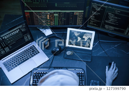 Top view. Young professional female hacker is indoors by computer with lot of information on displays Top view. Young professional female hacker is indoors by computer with lot of information on displays 127399790