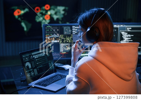 A lot of information on displays. Young professional female hacker is indoors by computer A lot of information on displays. Young professional female hacker is indoors by computer 127399808