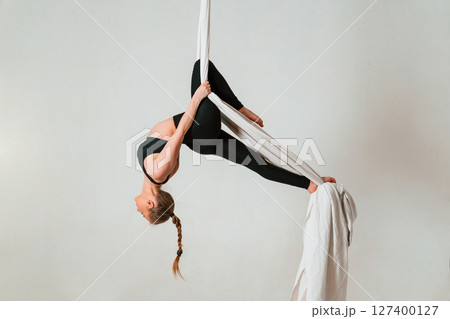 In the midair. Young beautiful woman doing fly yoga against white background In the midair. Young beautiful woman doing fly yoga against white background 127400127
