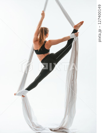 Conception of flexibility. Young beautiful woman doing fly yoga against white background 127400149