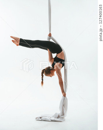 Stretching exercises. Young beautiful woman doing fly yoga against white background 127400163