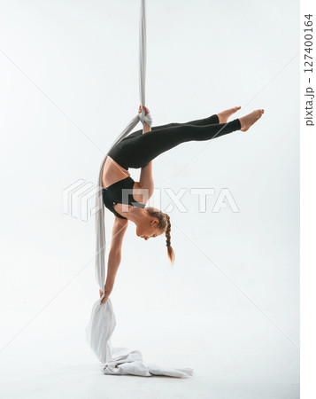 Stretching exercises. Young beautiful woman doing fly yoga against white background Stretching exercises. Young beautiful woman doing fly yoga against white background 127400164