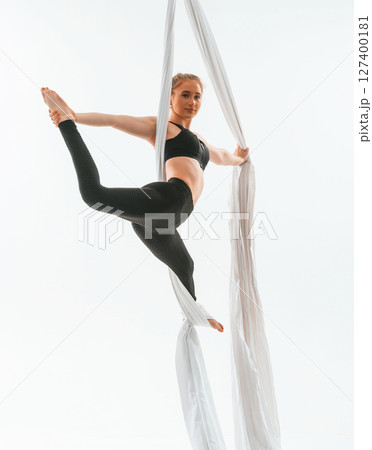 Professional occupation. Young beautiful woman doing fly yoga against white background 127400181