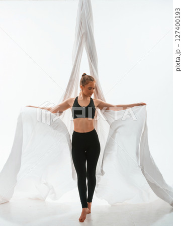 Young beautiful woman doing fly yoga against white background Young beautiful woman doing fly yoga against white background 127400193